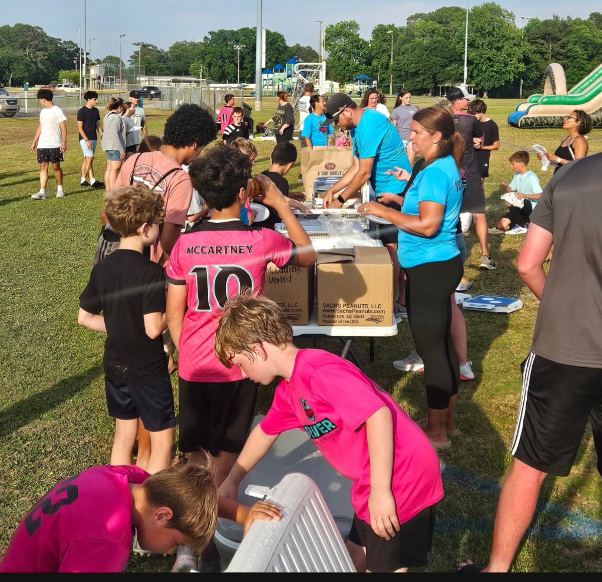 Kids and adults handing out food to the community at a Falcons United event