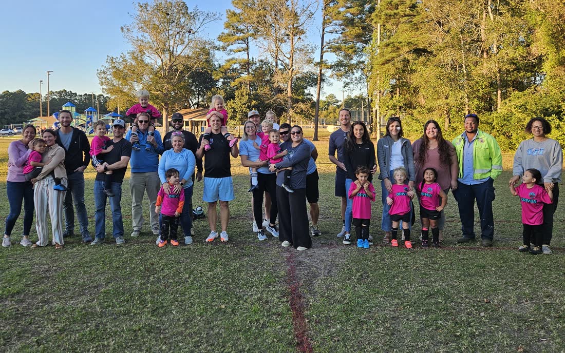 Falcons United families and young players in pink shirts lined up together on the field